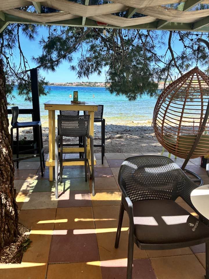 A beachside table beneath the trees beside the Adriatic